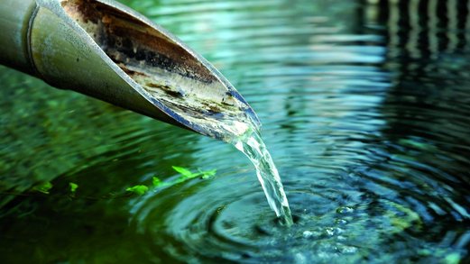klares Wasser fließt aus einem Bambusrohr in Gewässer