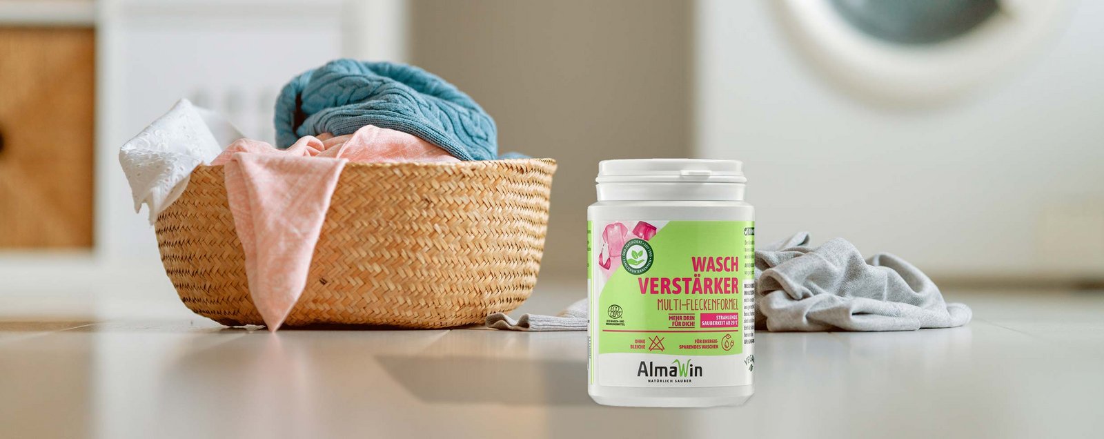 Eine Dose AlmaWin Waschverstärker vor Wäschekorb